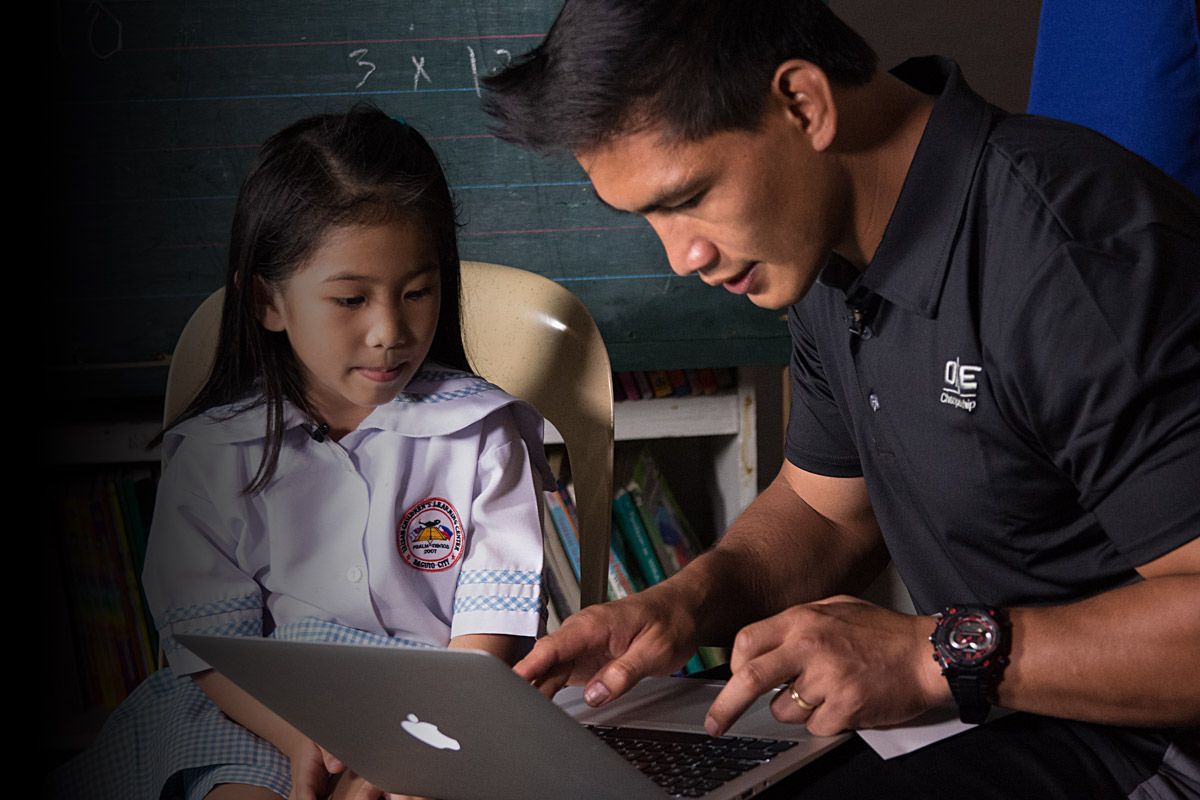 Former ONE Lightweight World Champion Eduard Folayang reads to a little girl during a Global Citizen initiative in Manila, Philipines